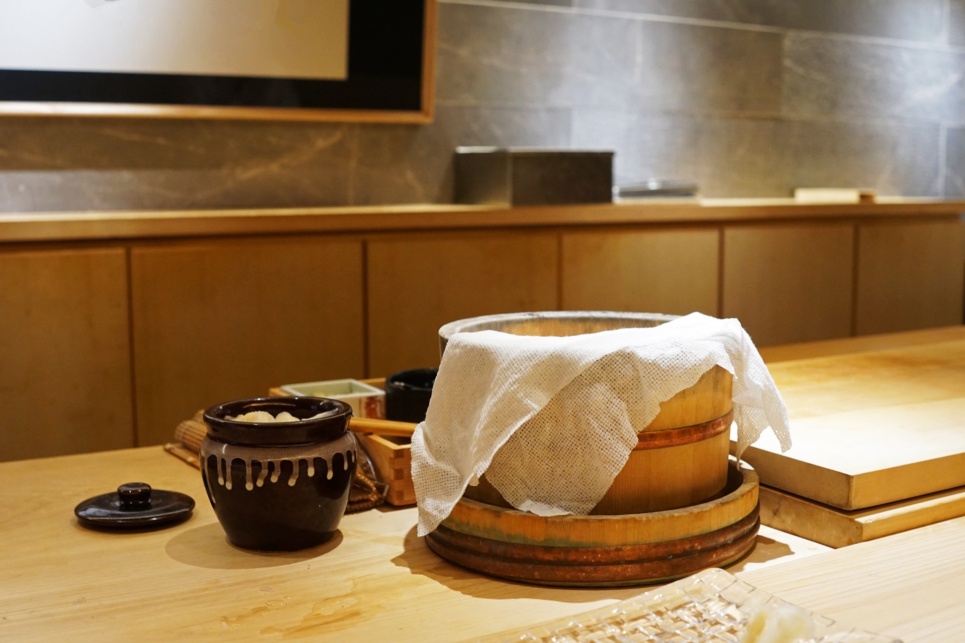 Interior bar design and counter decoration of Sushi and Sashimi preparation station decorated with wooden rice bowl, fermented ginger jar and fresh wasabi