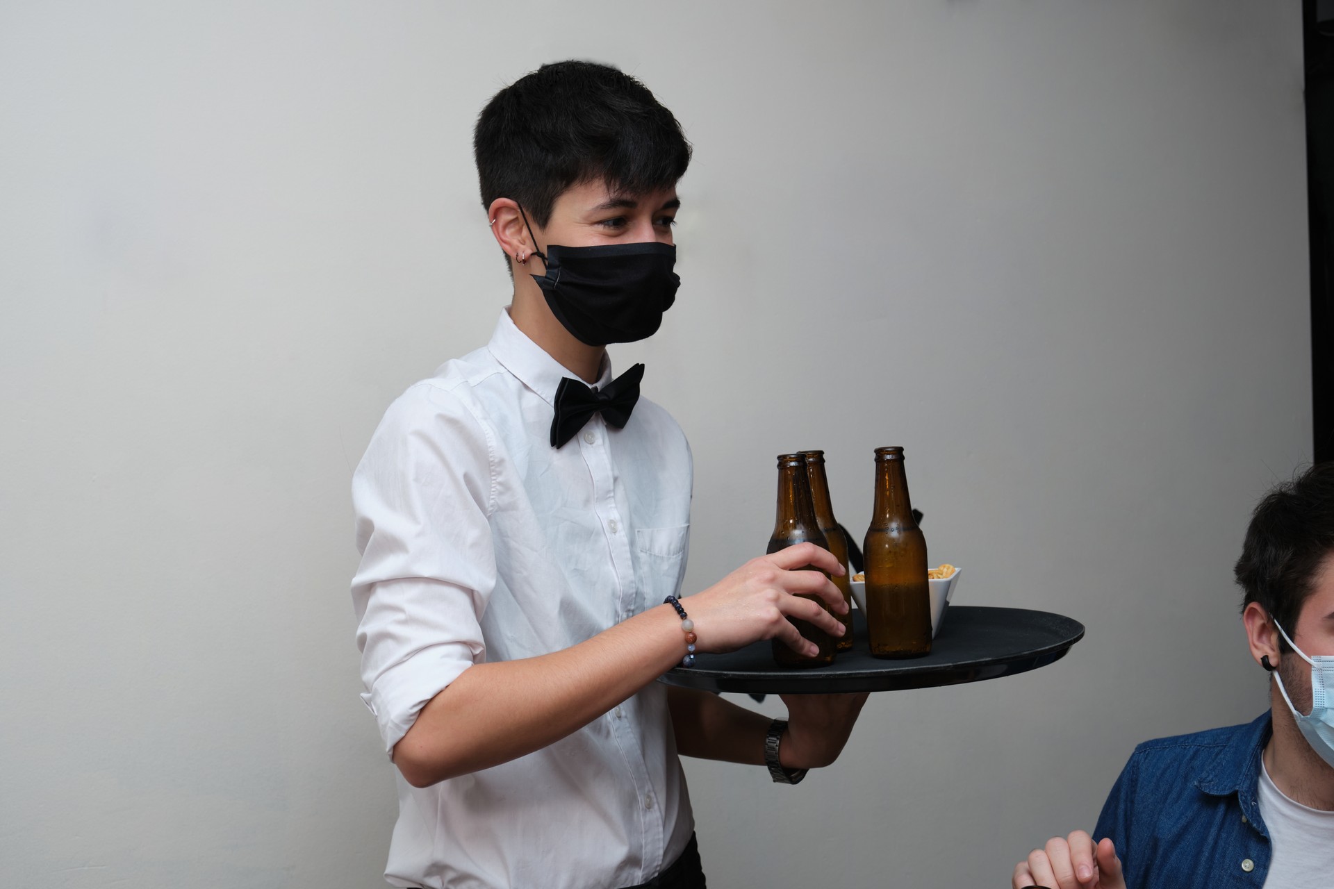 Waitress wearing protective face masks bringing drinks to her customers